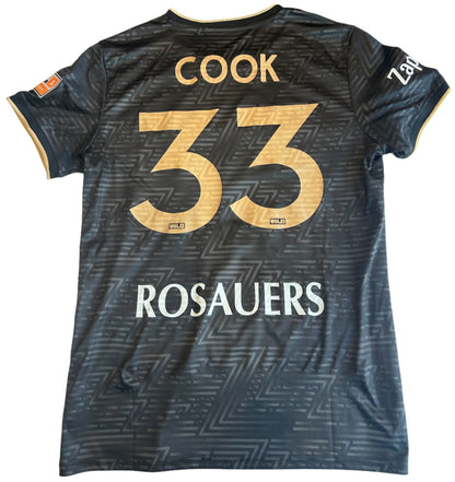 Black sports jersey with 'Cook 33' and 'Rosauers' on a white surface
